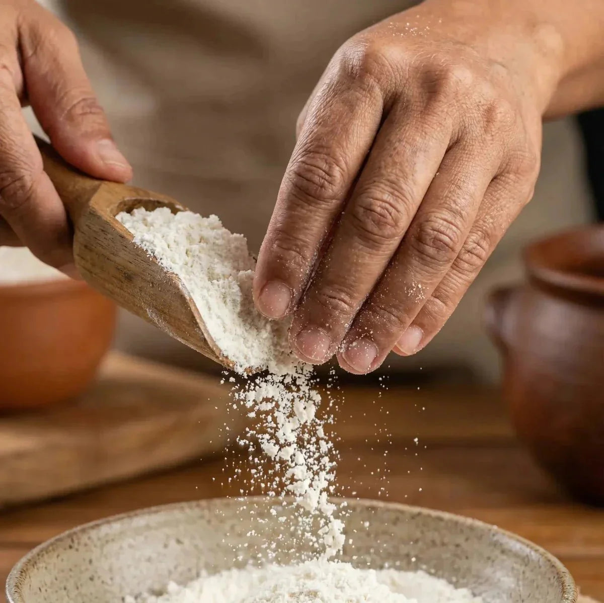 TANTIE, potato starch: hands pouring flour from a ladle into a bowl.