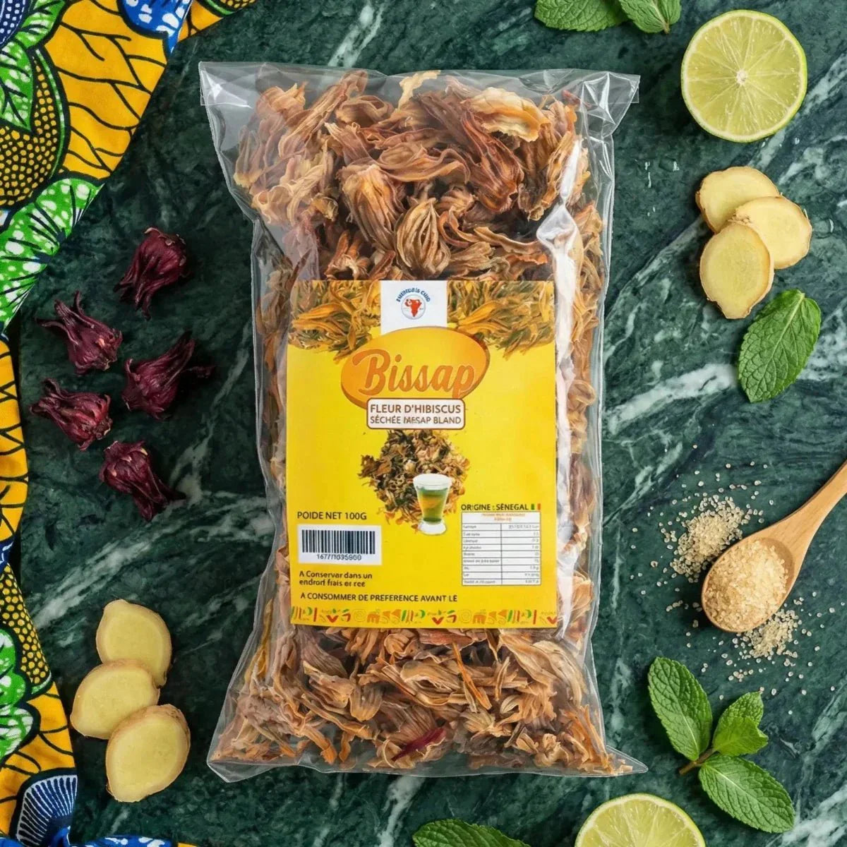 Bissap, gedroogde hibiscusbloem in zakje, omringd door limoen, gember, hibiscus.