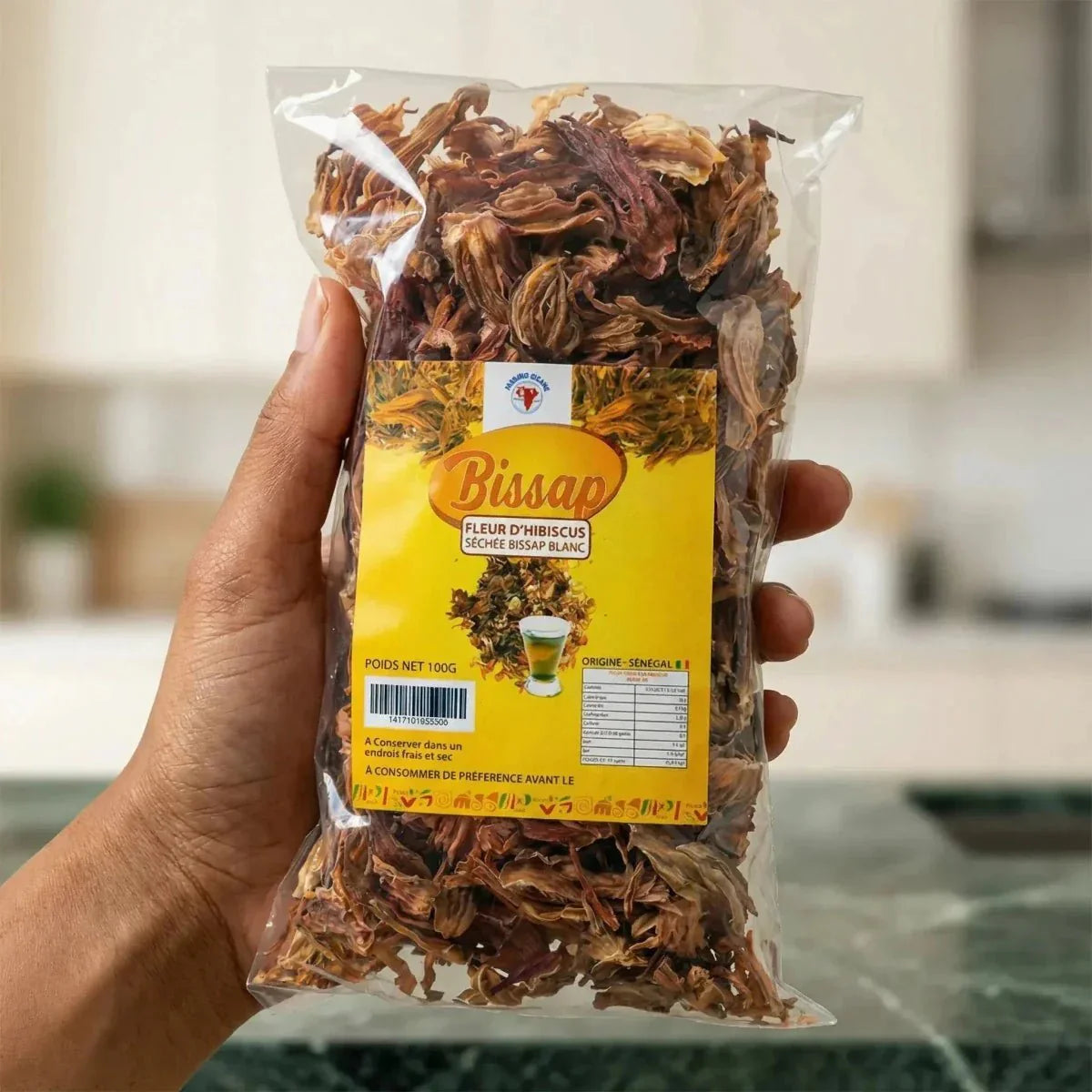 Zakje Bissap IMO CICANG, gedroogde witte hibiscusbloemen, vastgehouden in een keuken.