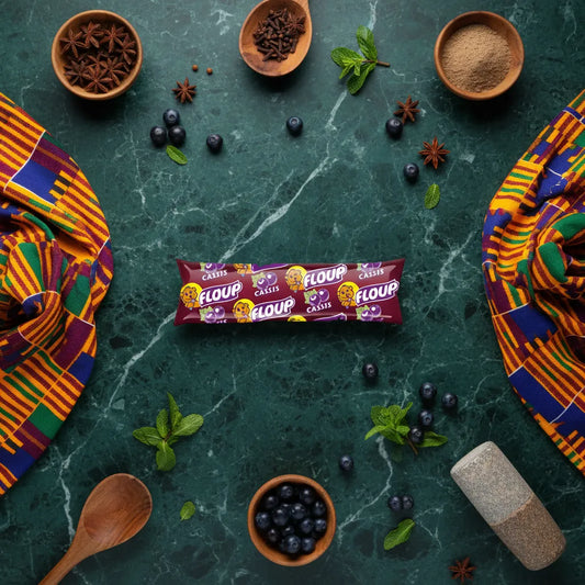 Glace Floup cassis posée sur une table décorée d'épices et de fruits, mettant en valeur son goût intense et son format pratique. Produit d'épicerie sucrée.