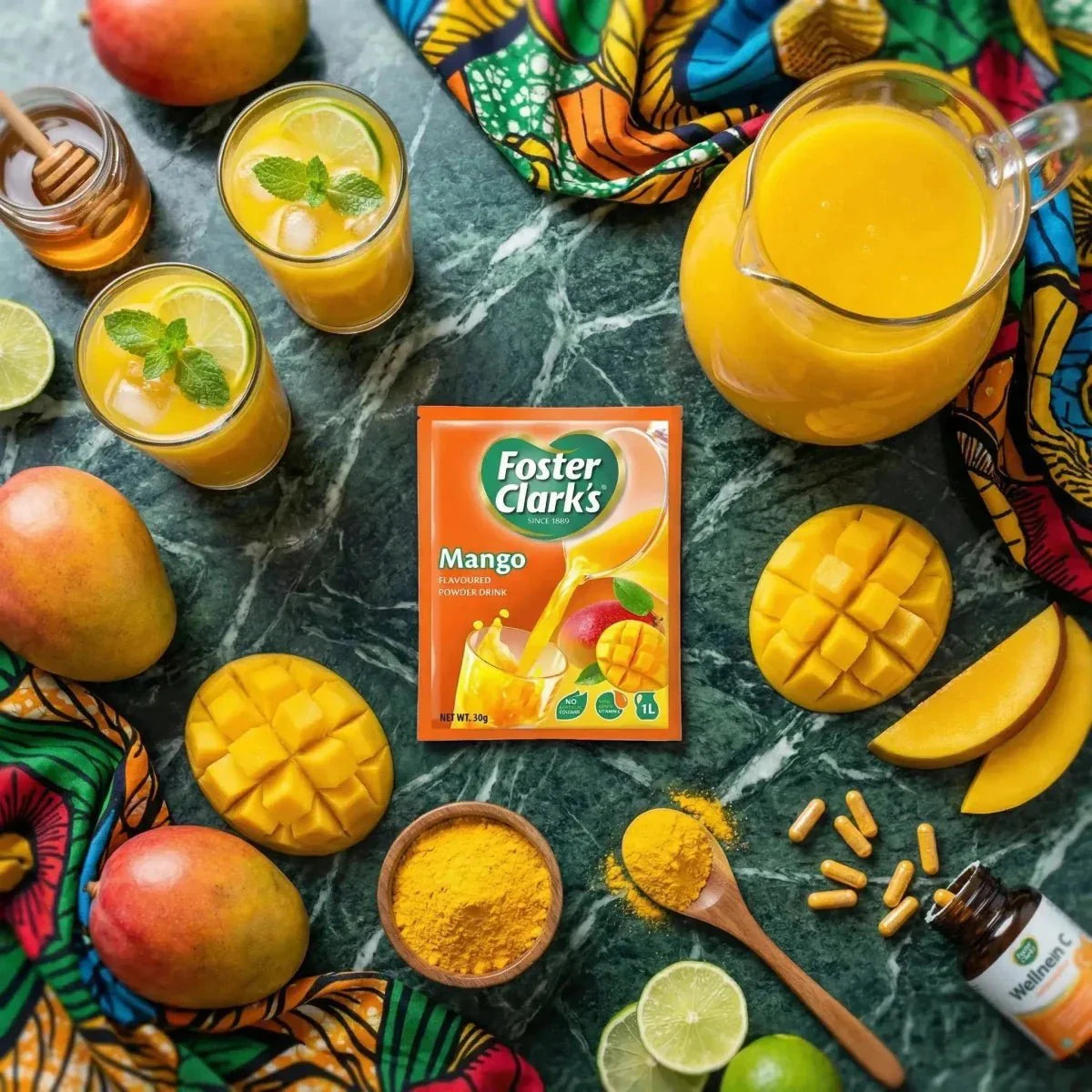 Jugo en polvo de mango FOSTER CLARKS rodeado de mangos frescos cortados, jugo y especias.