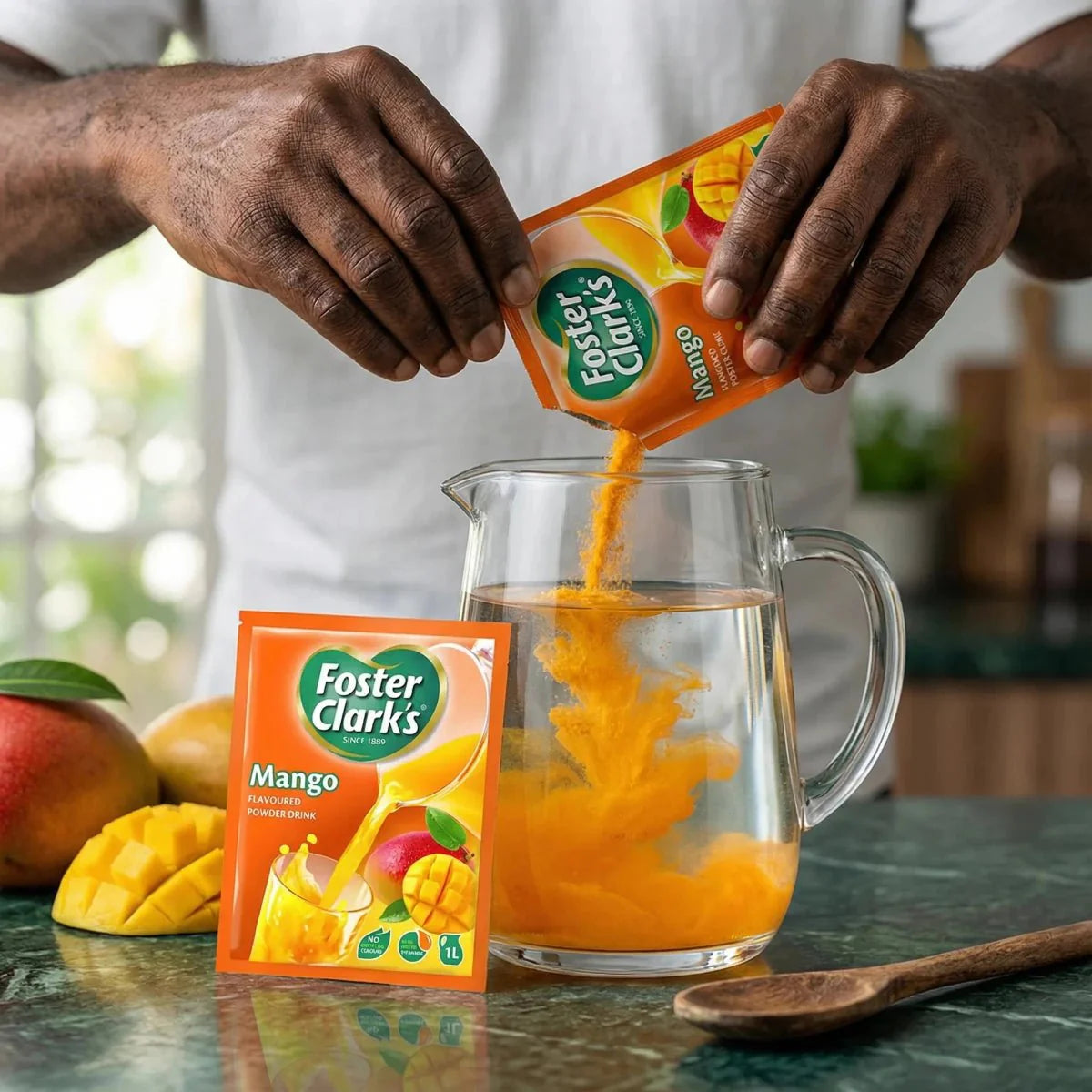 Jugo en polvo de mango Foster Clark's vertido en una jarra de agua. Paquetes de polvo.