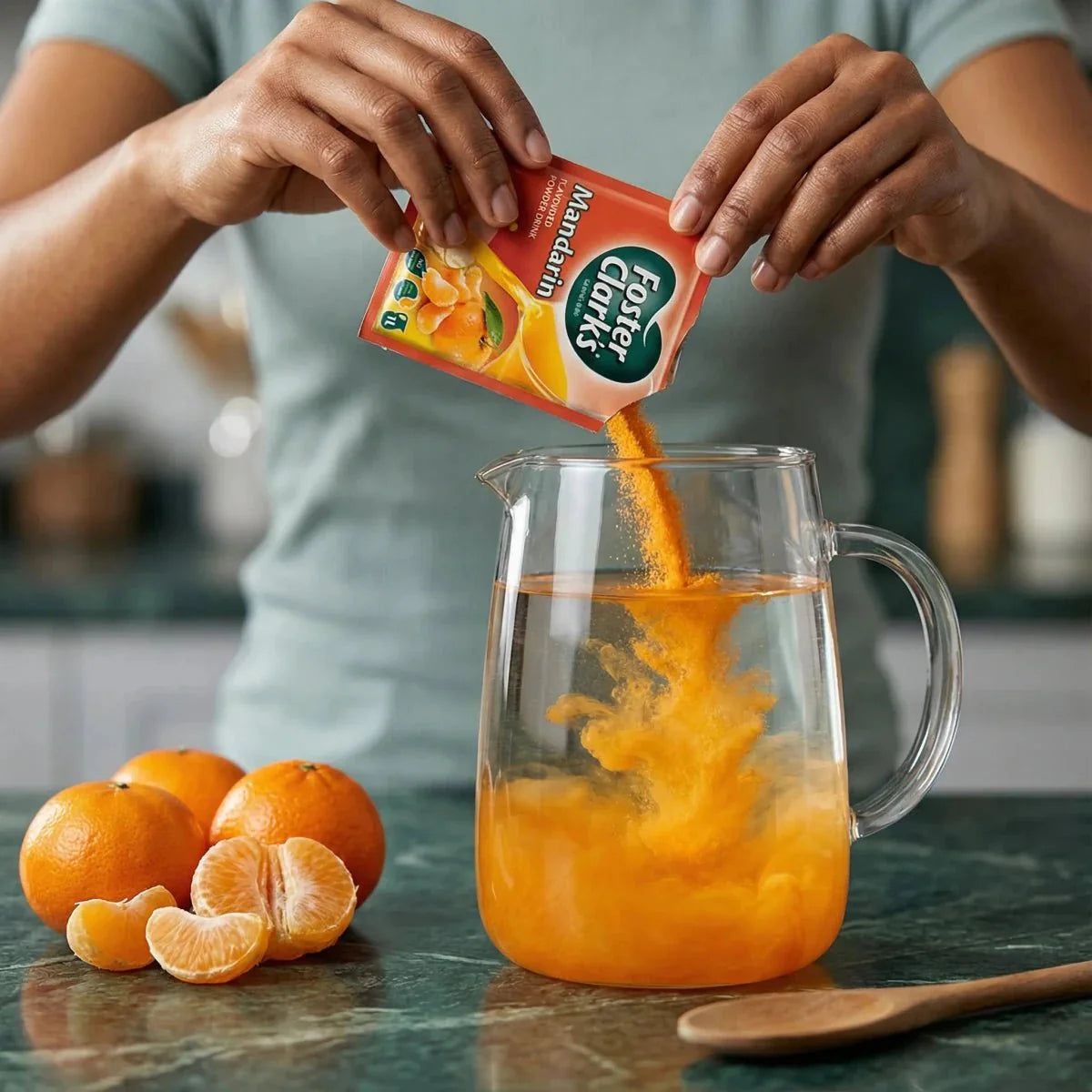 Mandarinen/Orangen-Pulsaft FOSTER CLARKS. Hände schütten Pulver in einen Wasserkrug.
