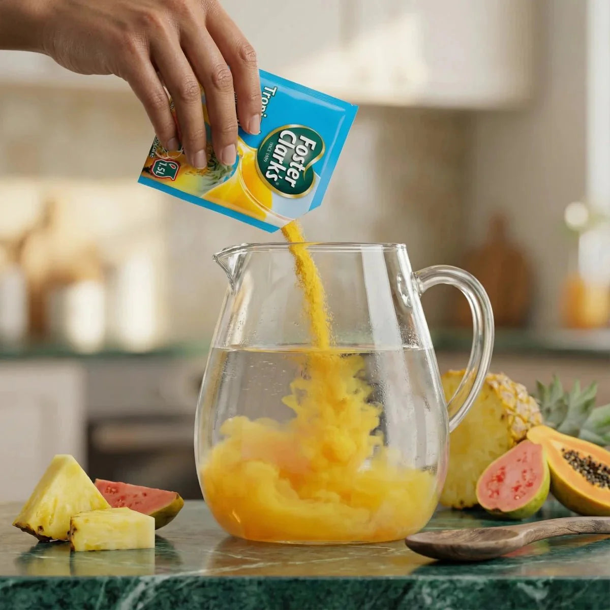 Jugo en polvo tropical FOSTER CLARKS vertido en una jarra de agua. Frutas exóticas.