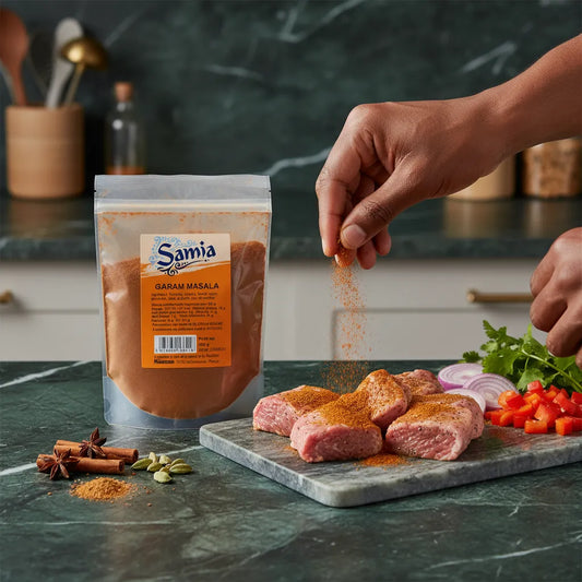 Main saupoudrant du Garam masala SAMIA sur des morceaux de viande crue, parfait pour assaisonnement avant cuisson ou marinade.