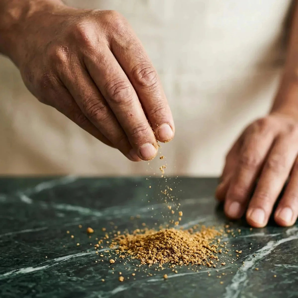 Gemahlener Gnangnan — 50g. Hand streut Pulver auf einen Marmortisch.