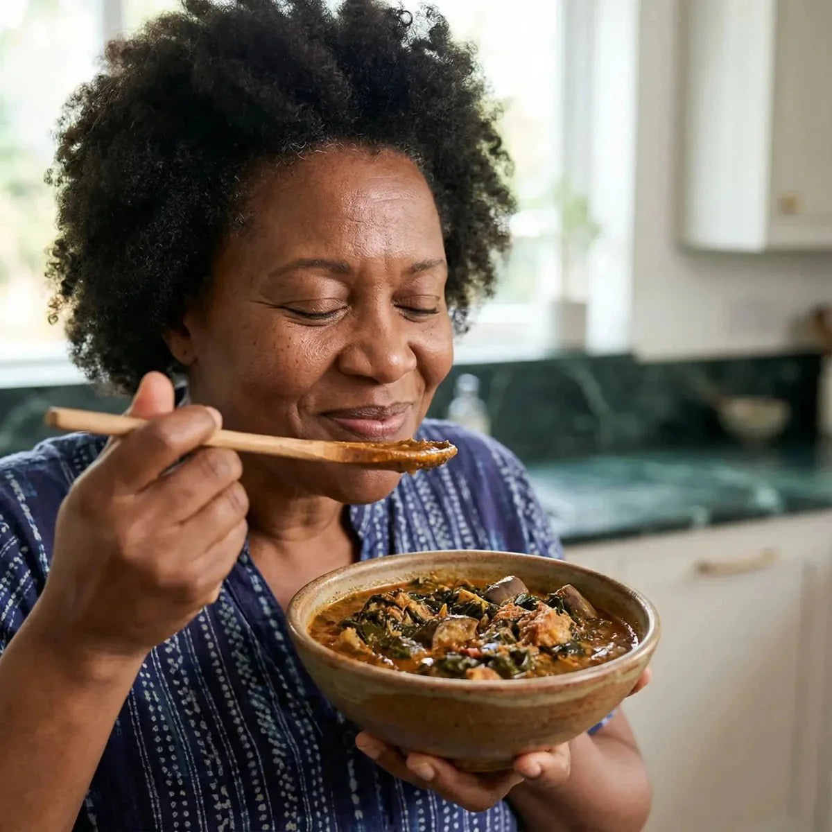 Gemahlener Gnangnan (50g). Frau genießt zu Hause ein dampfendes afrikanisches Gericht.