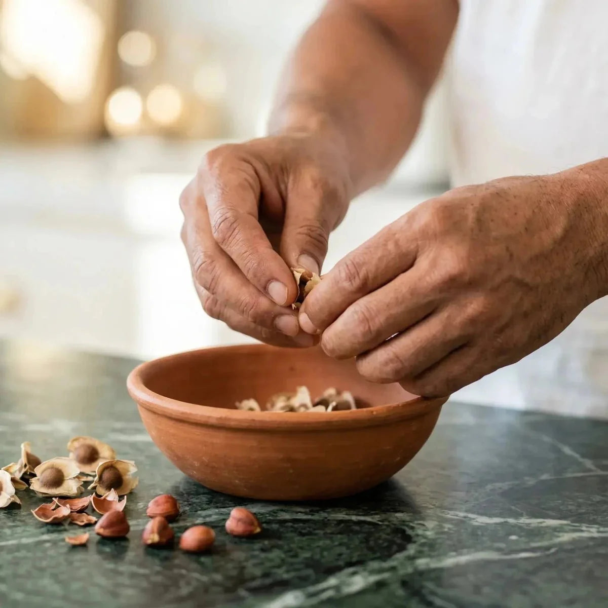 NUMBER ONE, Moringazaden. Handen die zaden pellen boven een aardewerken kom.