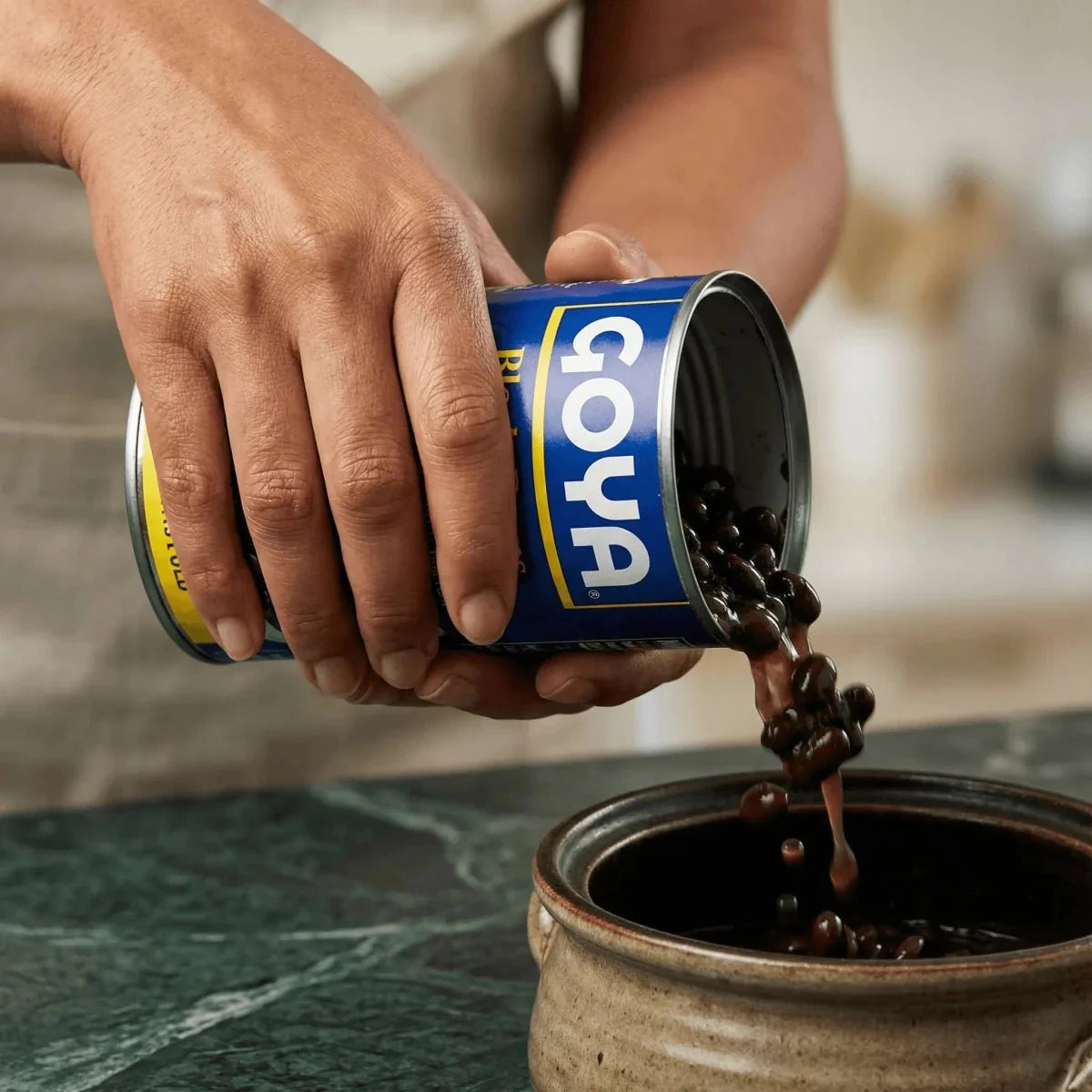 GOYA black beans (439g) poured from a blue can into a cooking container.