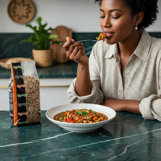 Femme dégustant un plat cuisiné aux haricots secs Cornilles LEGUMOR, posés sur un plan de travail vert dans une cuisine moderne.
