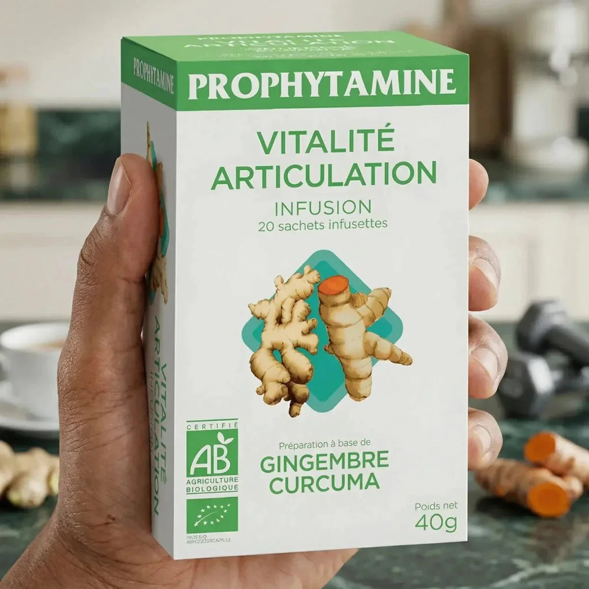Hand holding a box of BIO PROPHYTAMINE Vitality Joint Infusion (40g) against a kitchen background.