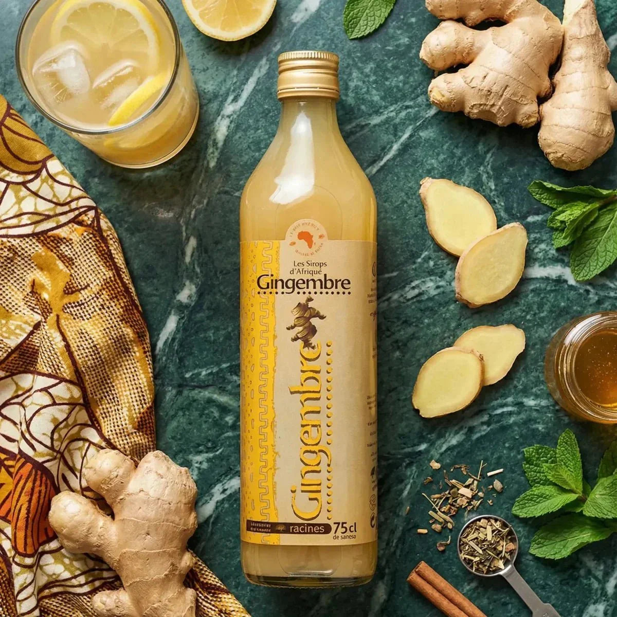 Konzentrierter Ingwersaft RACINES (75cL) auf einem Marmortisch mit Zitrone und Minze.