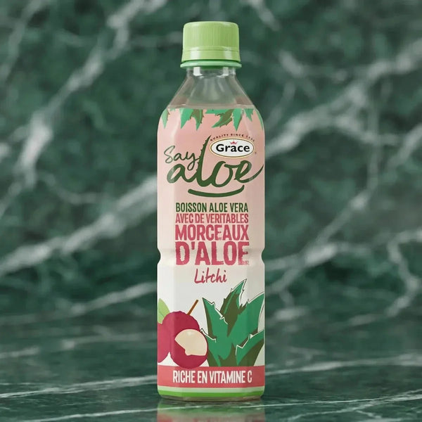 Aloe-Vera- und Litschi-Getränk von Grace, mit Aloe-Stücken, vor einem grün marmorierten Hintergrund.