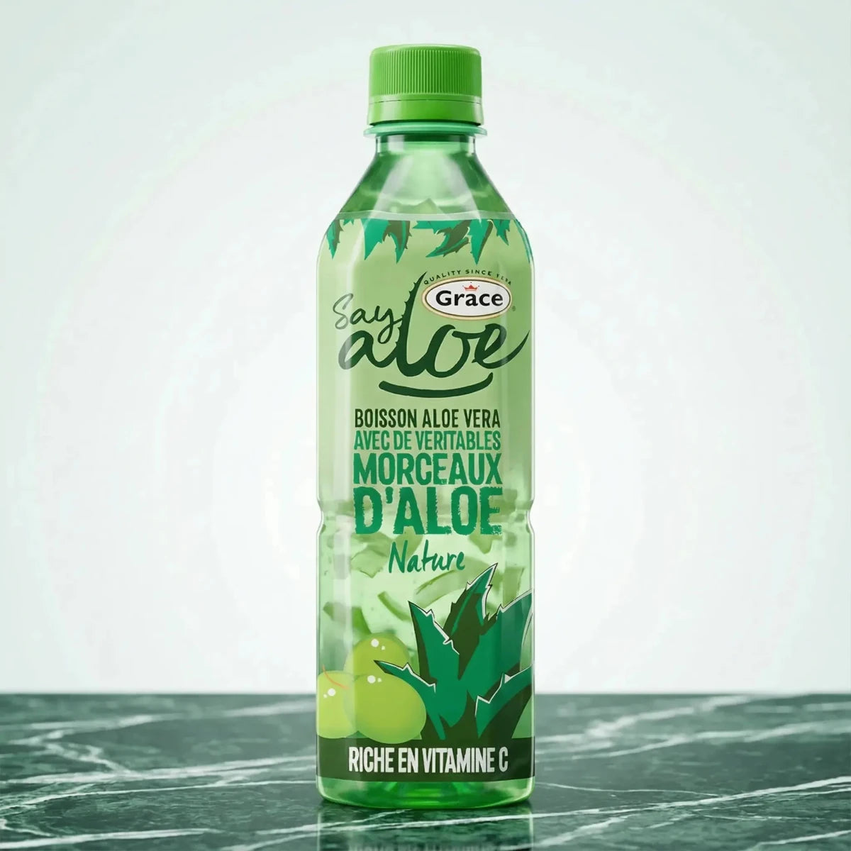 Aloëveradrank, door Grace, in een doorzichtige groene plastic fles op een groen-witte marmeren achtergrond.