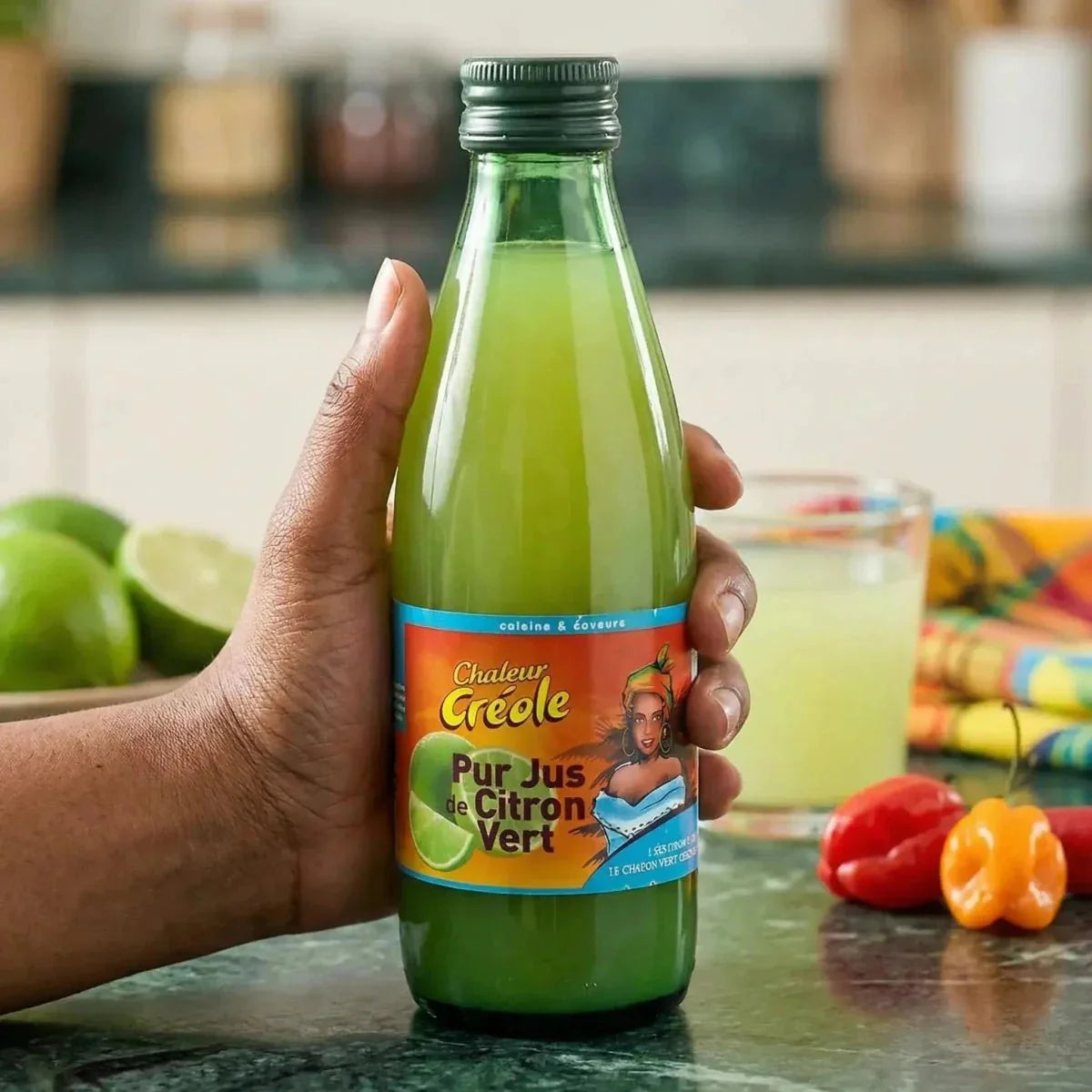 Hand holding a bottle of CHALEUR CRÉOLE lime juice.