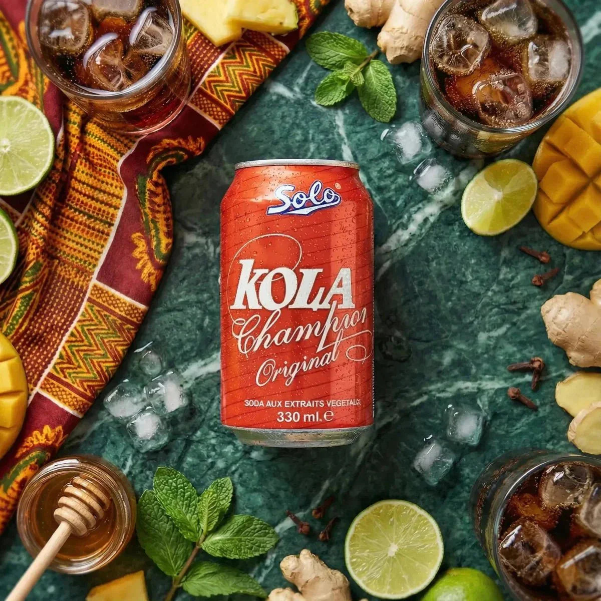Kola Champion SOLO 330mL on a marbled green background, surrounded by lime, mango, ginger, honey.