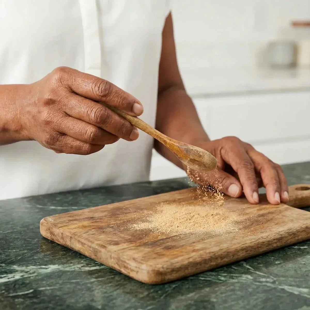 NUMBER ONE, Kpele powder: A person sprinkles powder from a wooden spoon onto one.