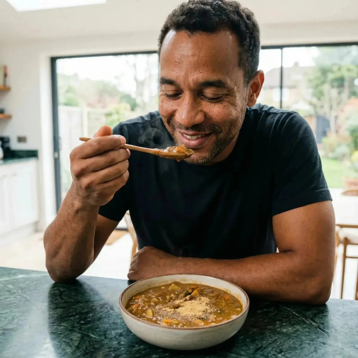 Kpele powder NUMBER ONE. Smiling man eating a soup garnished with Kpele powder with a.
