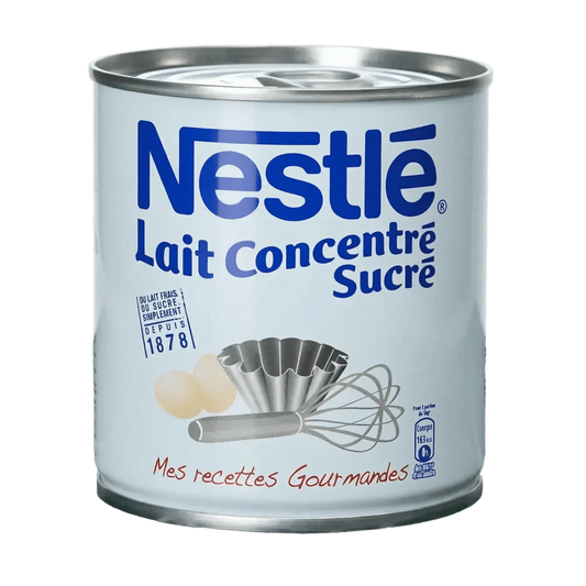 Blik gezoete gecondenseerde melk van Nestlé. Geëtaleerd met eieren, muffinvorm en garde.