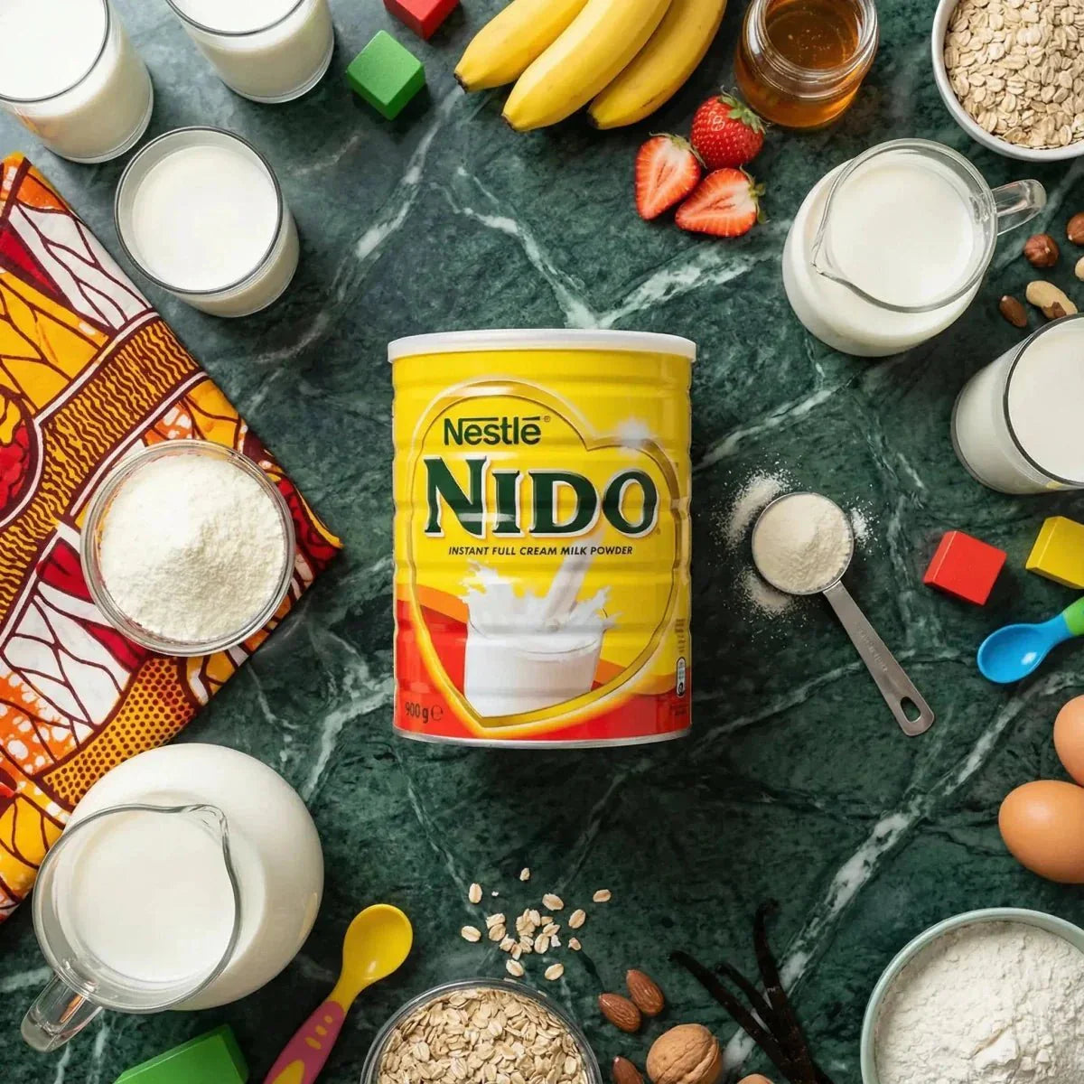 Nestlé NIDO powdered milk surrounded by milk, fruits, cereals, and eggs on a marbled green background.