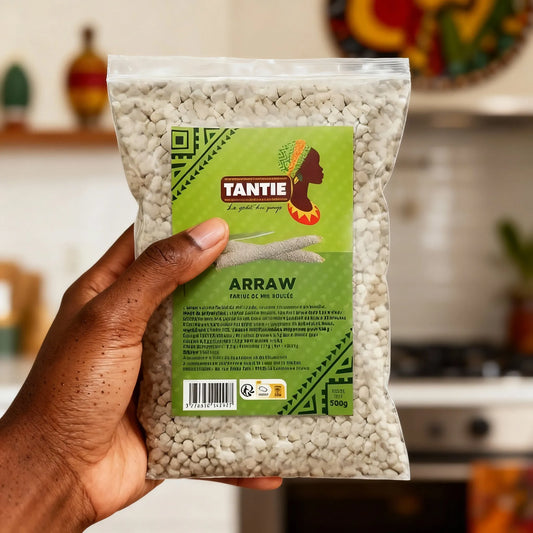 Main tenant un sachet Arraw TANTIE 500g dans une cuisine, mélange de mil roulé prêt à l'emploi pour une texture légère et parfumée.