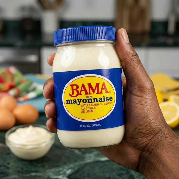 Mayonnaise crémeuse avec un soupçon de citron de BAMA, dans un pot en verre, tenu par une main.
