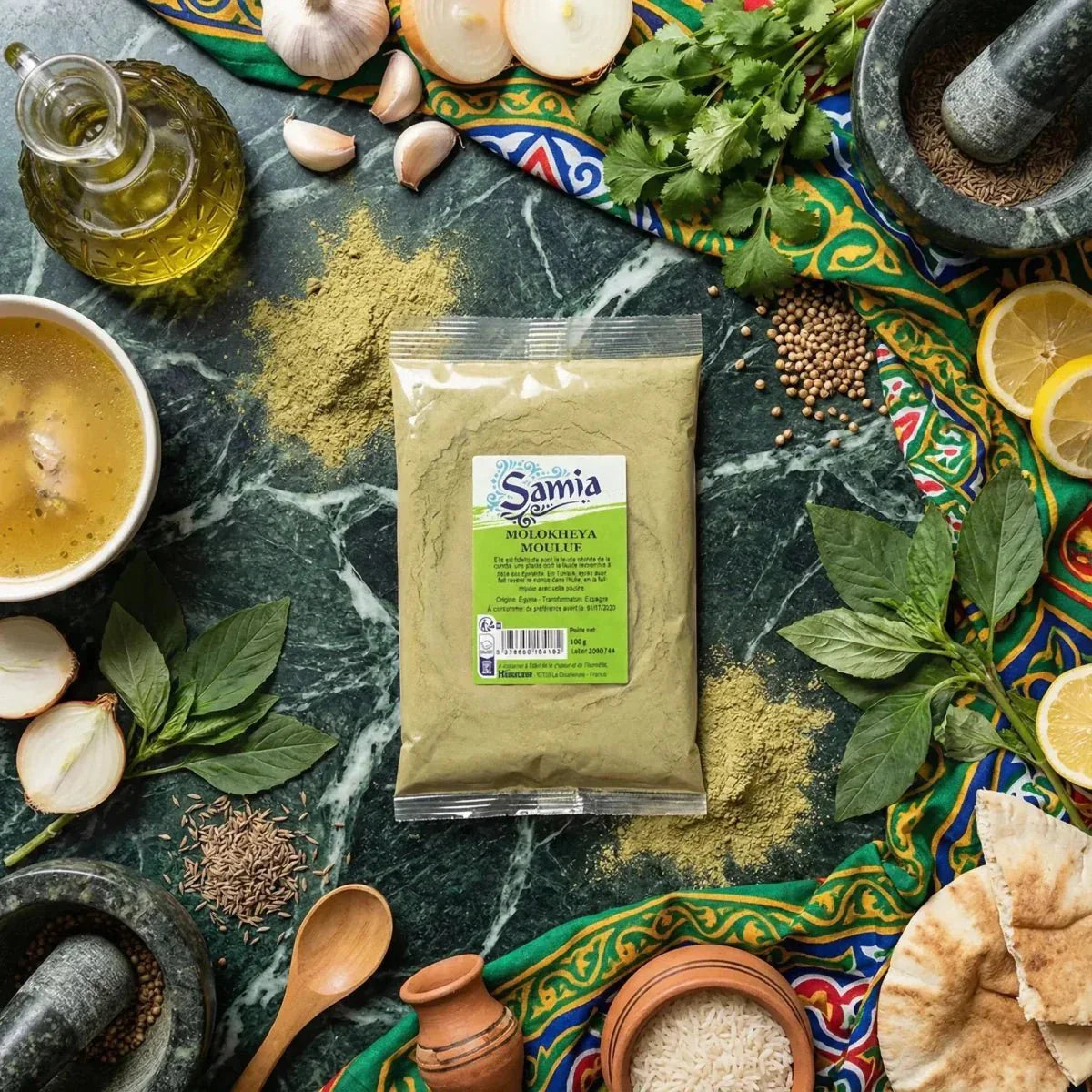 Molokheya macinata SAMIA su un tavolo con ingredienti: aglio, limone, erbe, olio, spezie.