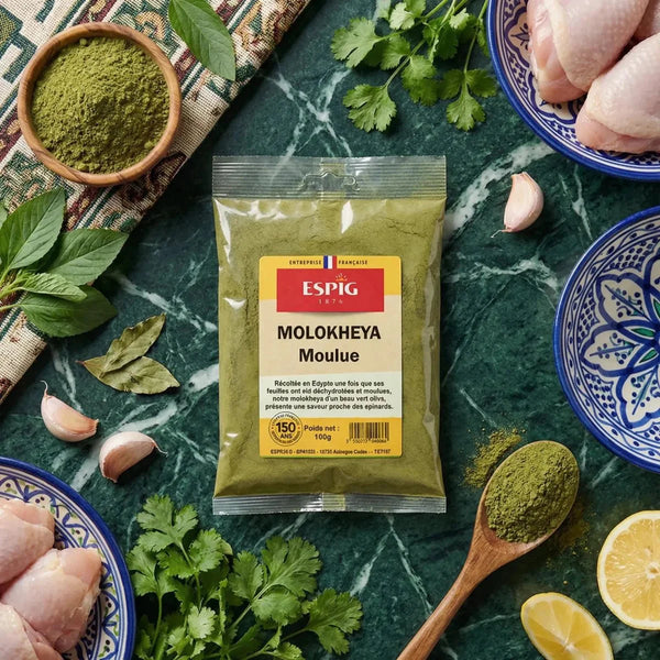 Sachet Molokheya moulu ESPIG, 100g, entouré d'ingrédients : poulet, citron, ail, herbes.