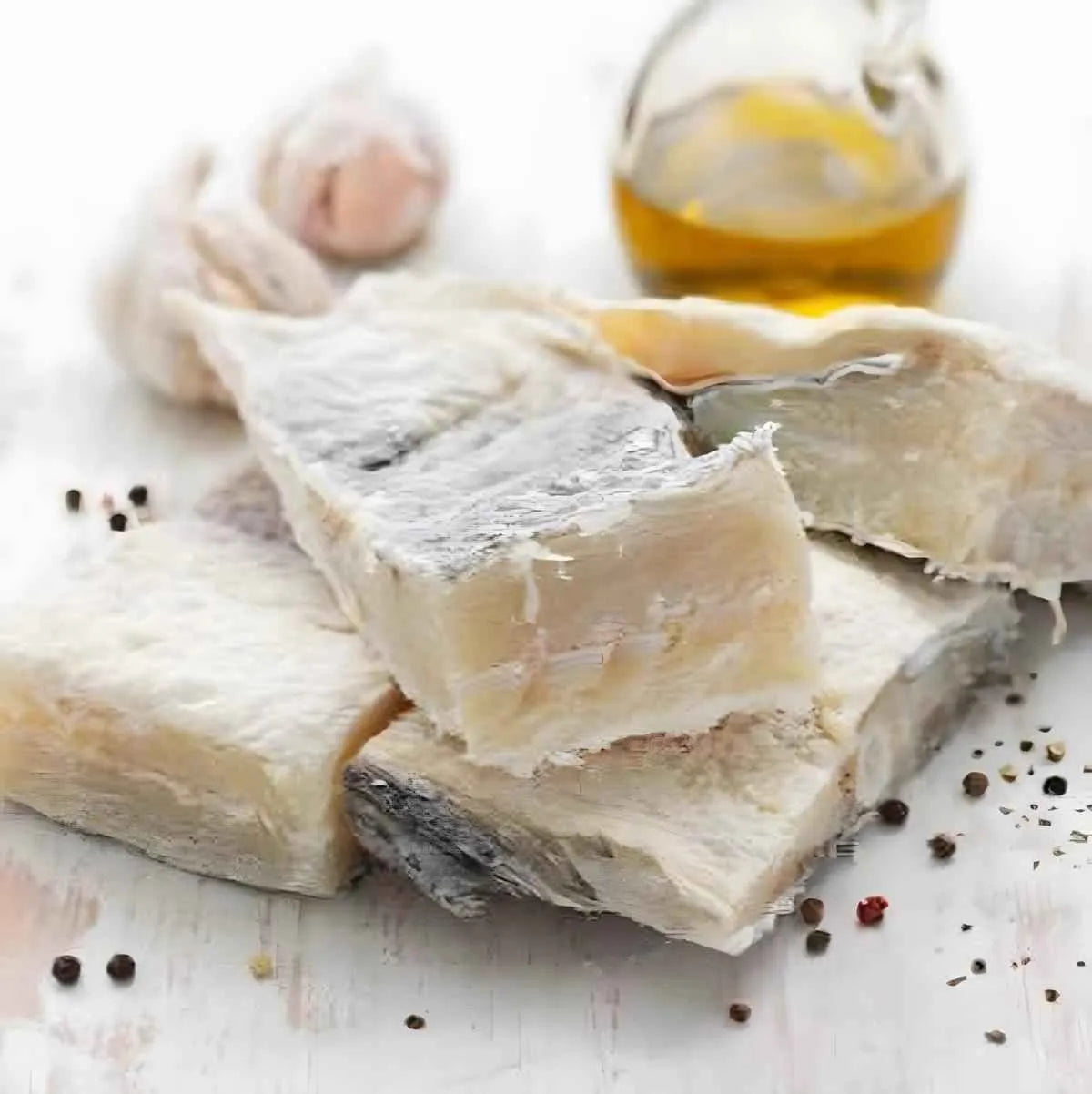 Morceaux de morue salée séchée avec huile d’olive, ail et poivre. Produit de la mer raffiné pour cuisine méditerranéenne ou créole.