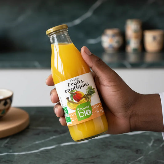 Main tenant une bouteille de nectar Fruits Exotiques Bio RACINES, boisson bio tropicale au goût naturel et rafraîchissant.