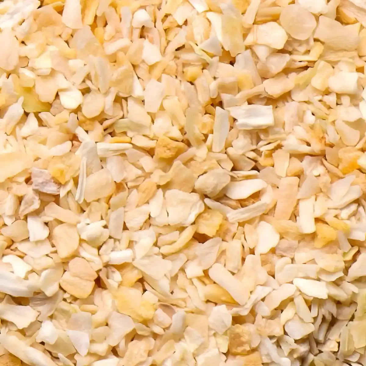 Gros plan sur la texture de la semoule d'oignon blanc SAMIA, condiment sec idéal pour assaisonner plats salés et sauces maison.