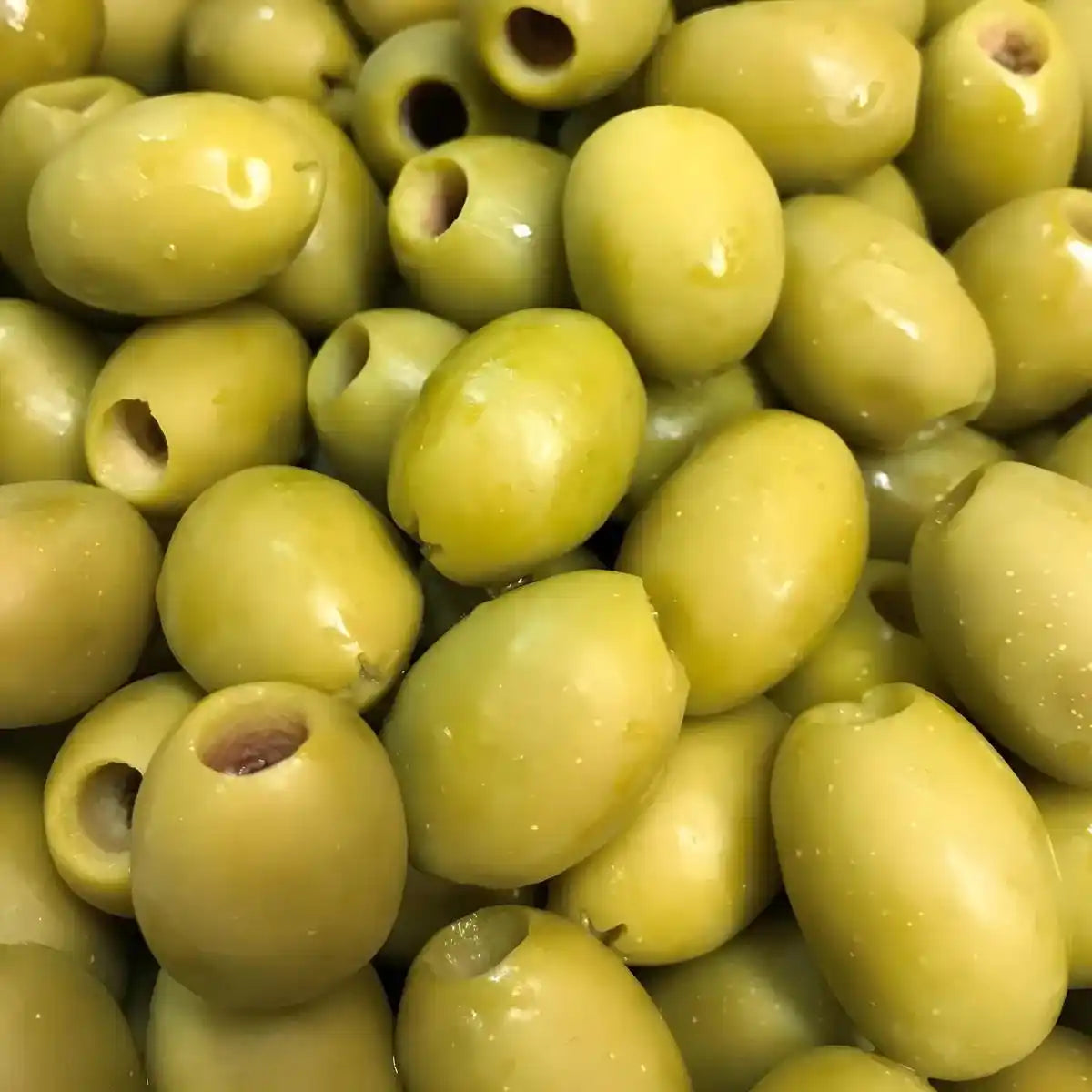 Gros plan sur des olives vertes dénoyautées SAMIA brillantes et fermes, idéales pour apéritifs ou plats méditerranéens.