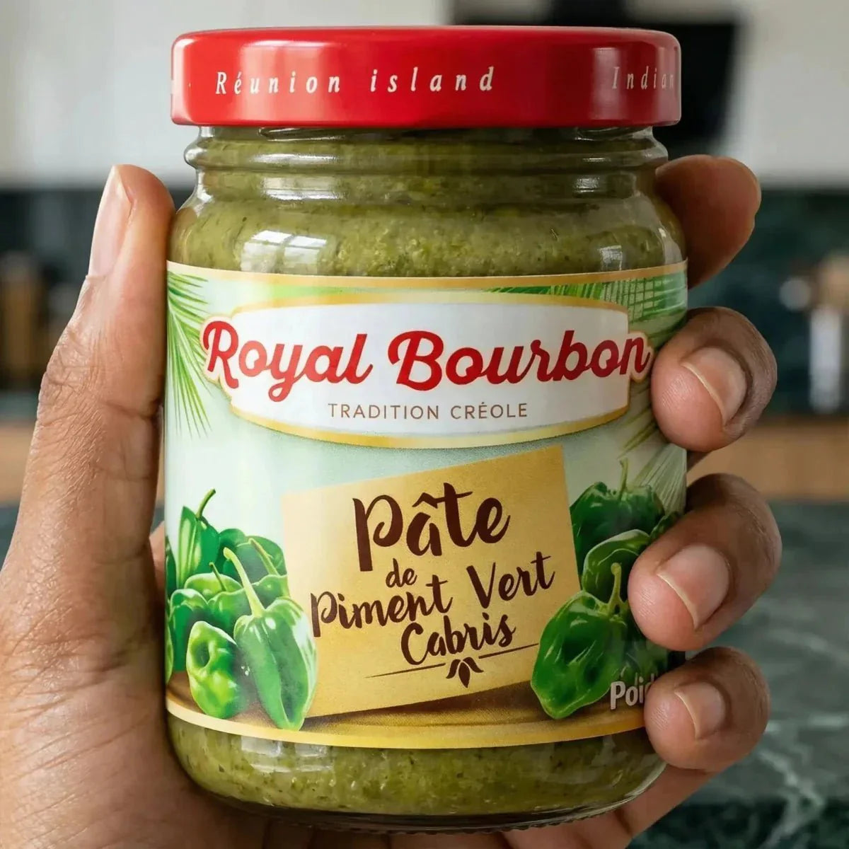 Eine Hand hält ein Glas grüne Pimentpaste Cabris ROYAL BOURBON (90g).