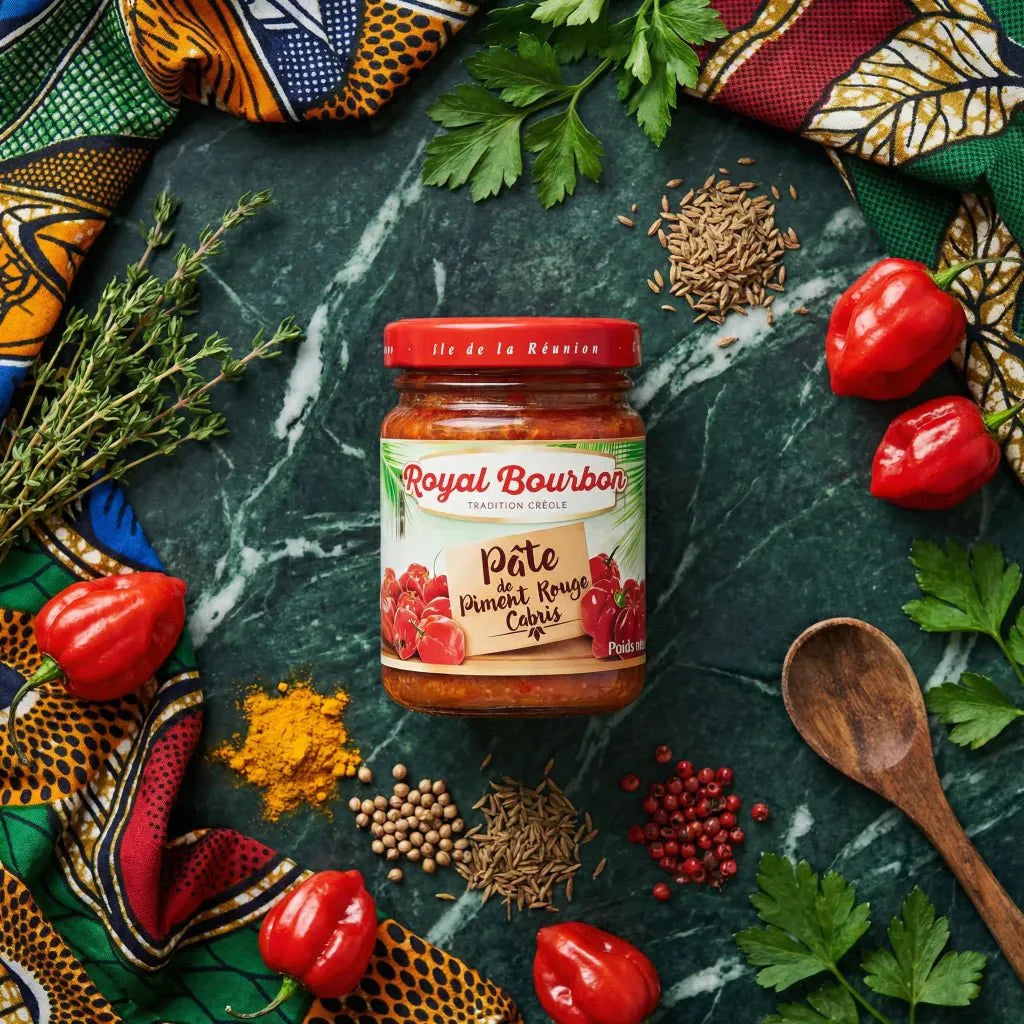 Pasta di Peperoncino Rosso Cabris Royal Bourbon 90g circondata da spezie riunionesi su sfondo verde.