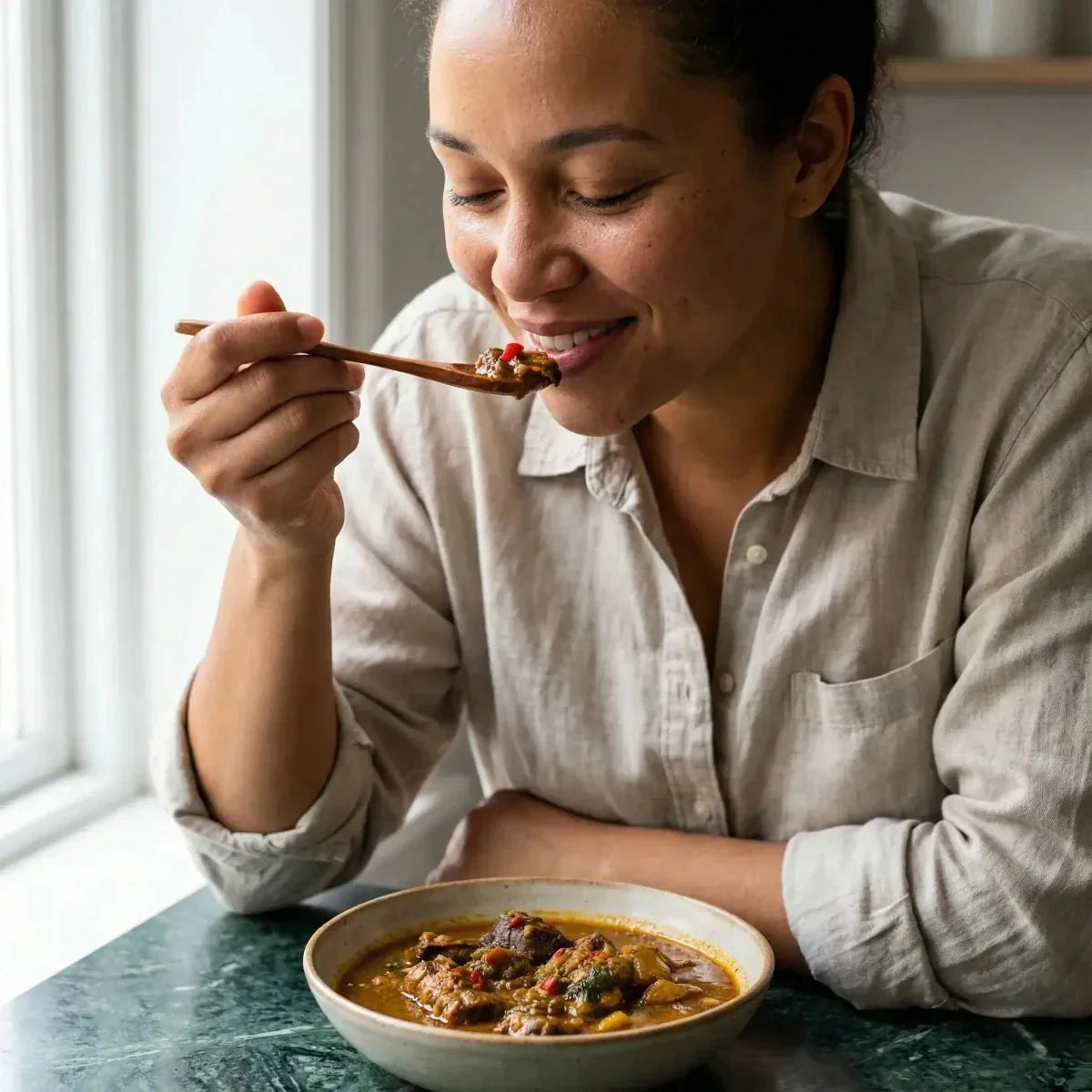 Frau genießt ein Gericht mit Akpi-Kablè NUMBER ONE Chili aus Foufou.