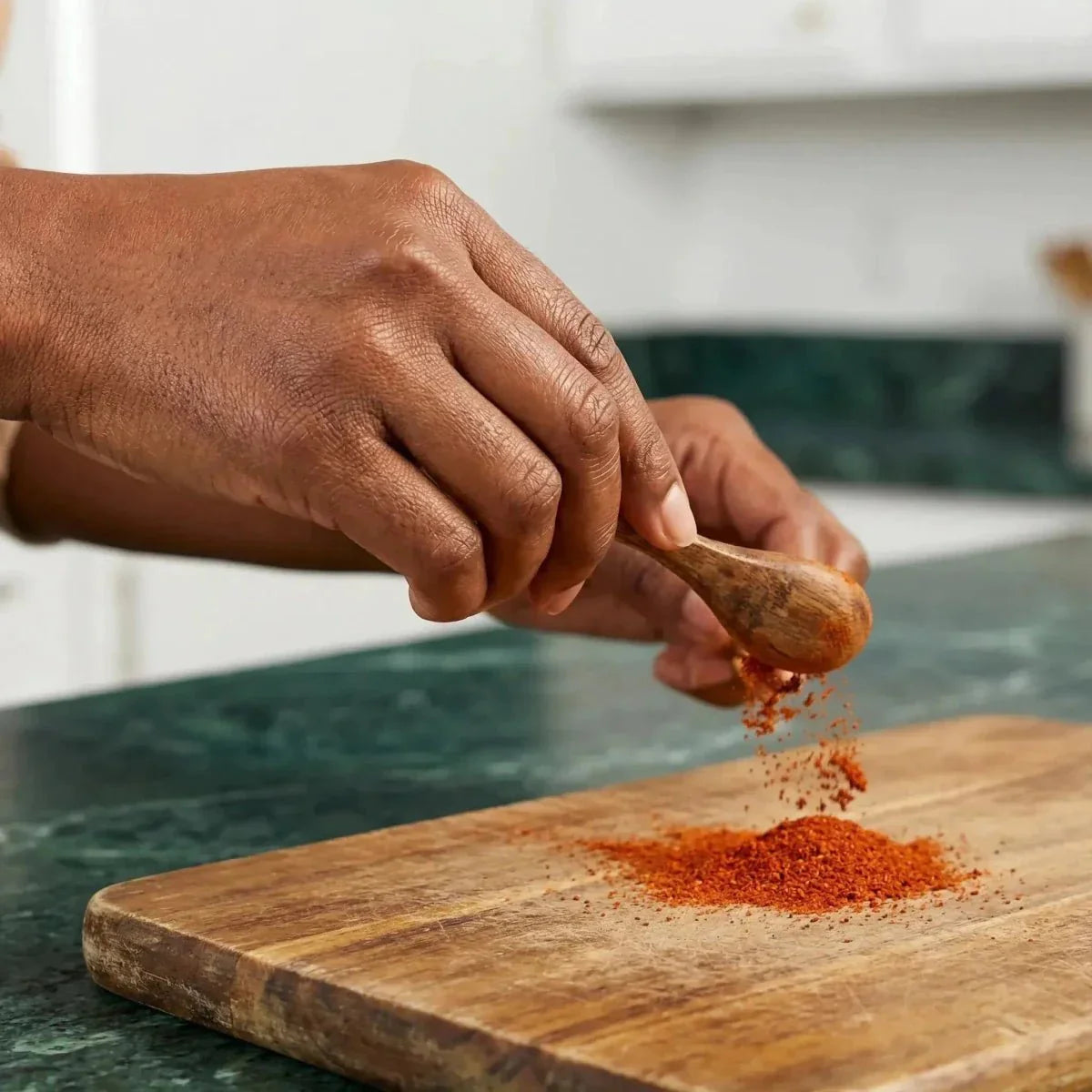 Ground hot chili SAMIA poured from a wooden spoon onto a cutting board.
