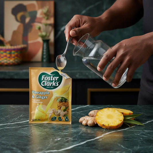 Préparation du jus poudre ananas gingembre FOSTER CLARKS avec eau dans une carafe. Boisson instantanée idéale pour une consommation rapide.