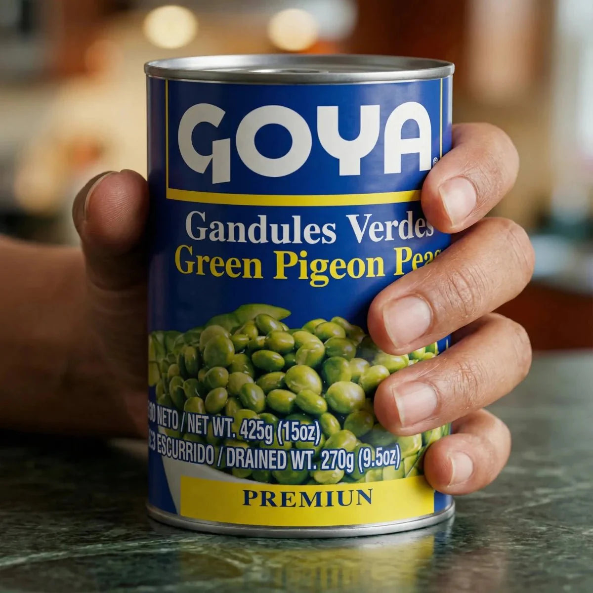 Eine Hand hält eine blaue Dose grüne Angolapetersilie von GOYA auf einer Küchentheke.