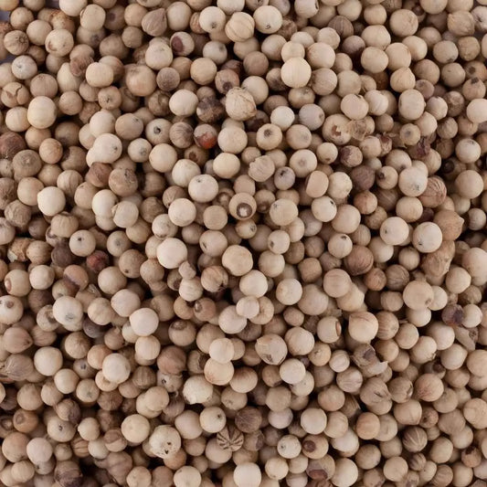 Gros plan sur les grains de poivre de Penja blanc, épice précieuse au goût subtil issue des terres volcaniques camerounaises.