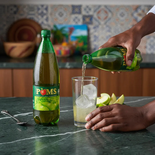 Versement du soda goût pomme POM'S dans un verre avec glaçons, boisson rafraîchissante idéale pour les instants de détente à la maison.