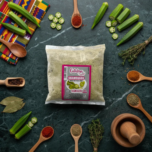 Sachet de poudre de gombo Gbamougou entouré d'épices et légumes frais comme le gombo, sur fond de marbre vert foncé.