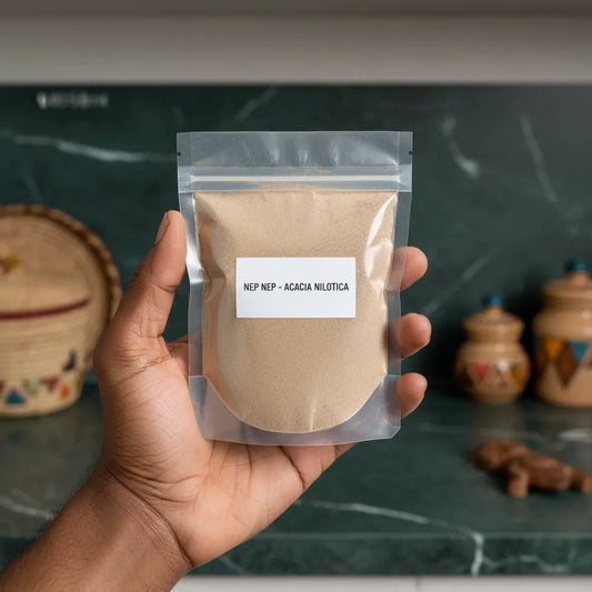Main tenant un sachet de Nep Nep Poudre | Épice Africaine 100% Naturelle - NKOSI devant un plan de travail de cuisine africaine.