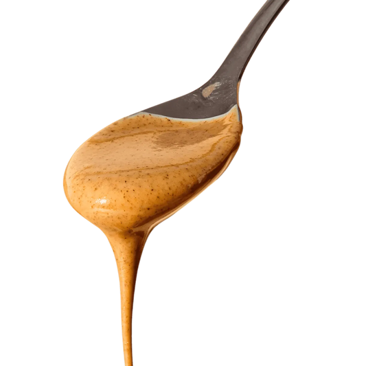 Texture onctueuse de la purée d'amande complète RACINES BIO sur une cuillère, idéale pour recettes sucrées ou salées - ÉPICERIE SUCRÉE NKOSI.