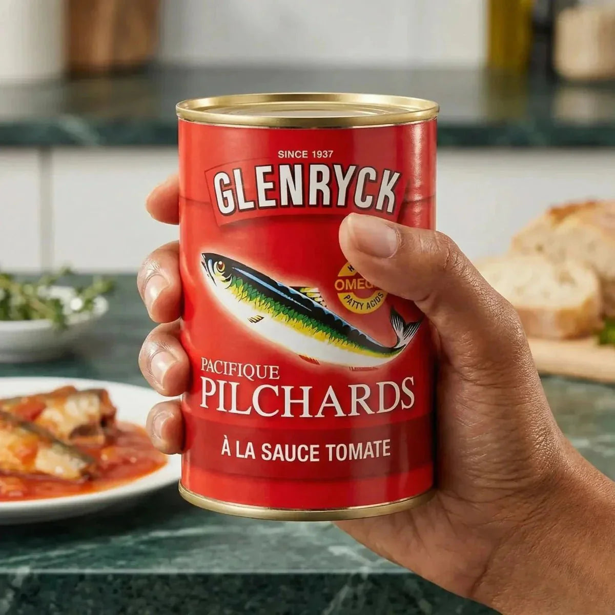Pilchard sardines in tomato sauce by Glenryck, held in one hand.