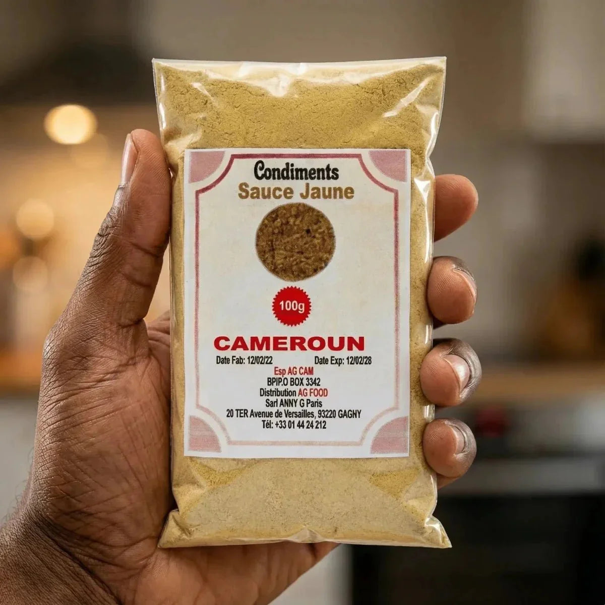 Zakje gele sauskruiden "CAMEROUN" 100g in de hand gehouden, met fabrikantinformatie.