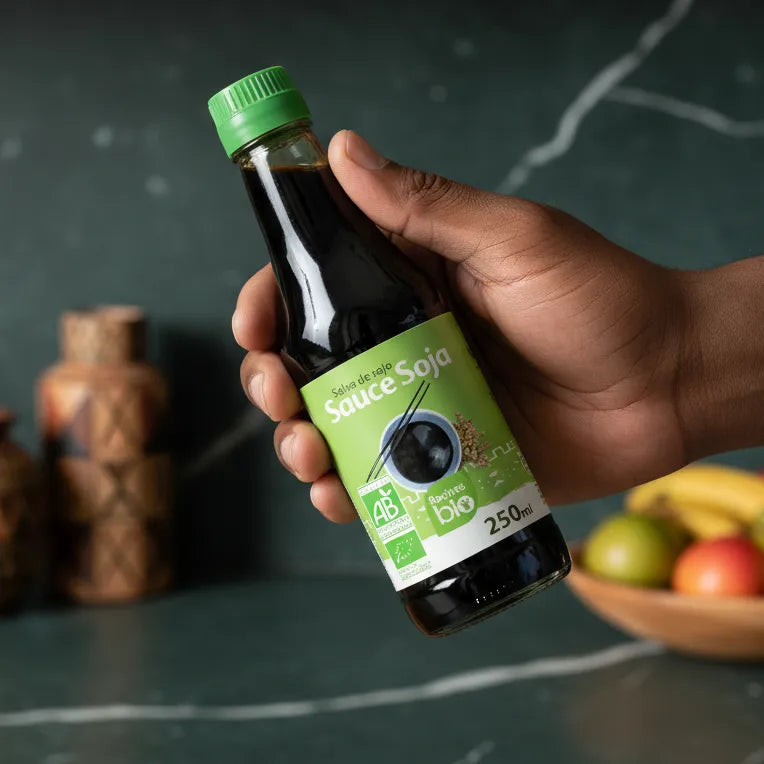 Main tenant une bouteille de sauce soja RACINES BIO 250ml, produit bio certifié pour cuisine saine et savoureuse au quotidien.