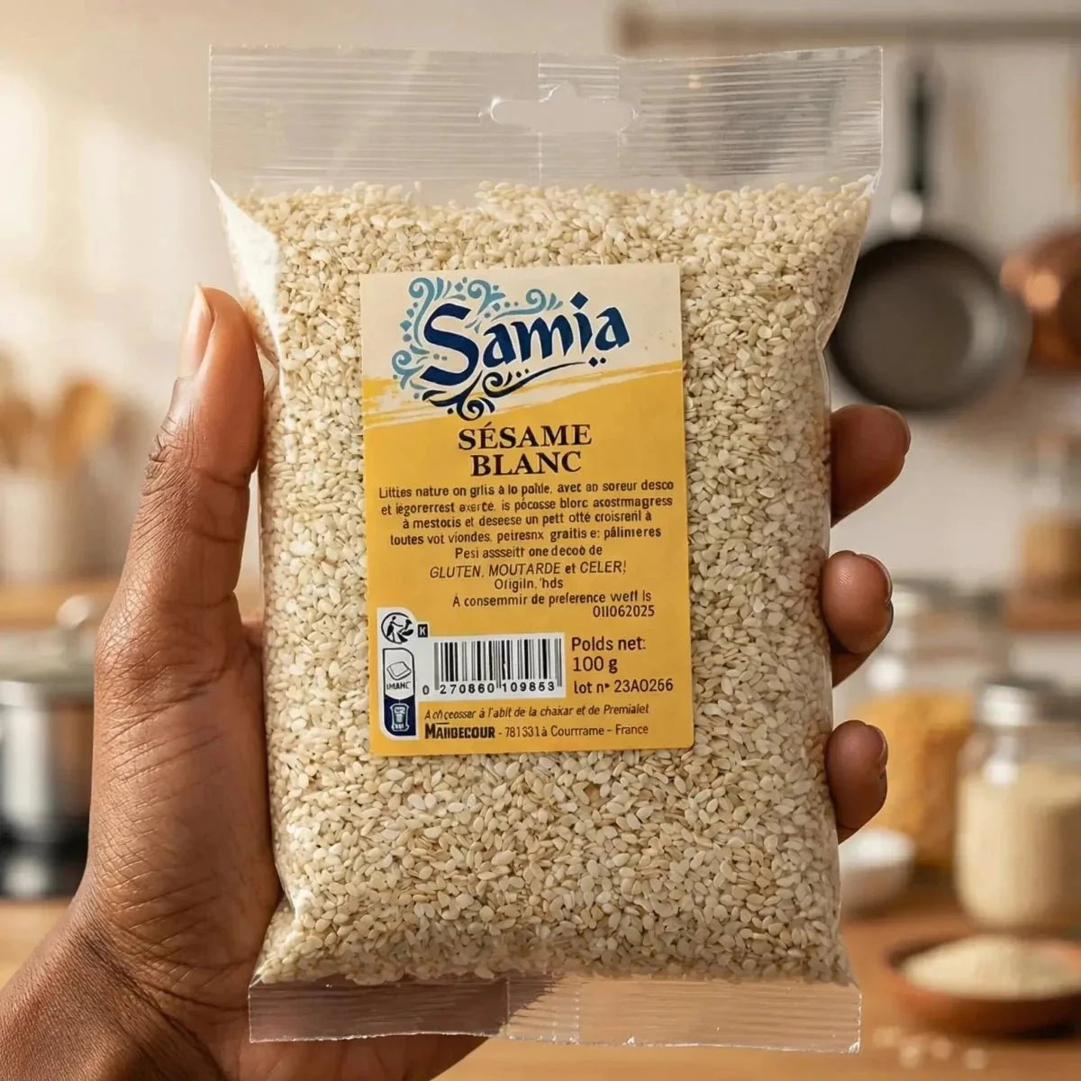 Sachet de sésame blanc Samia tenu à la main. Cuisine en arrière-plan.