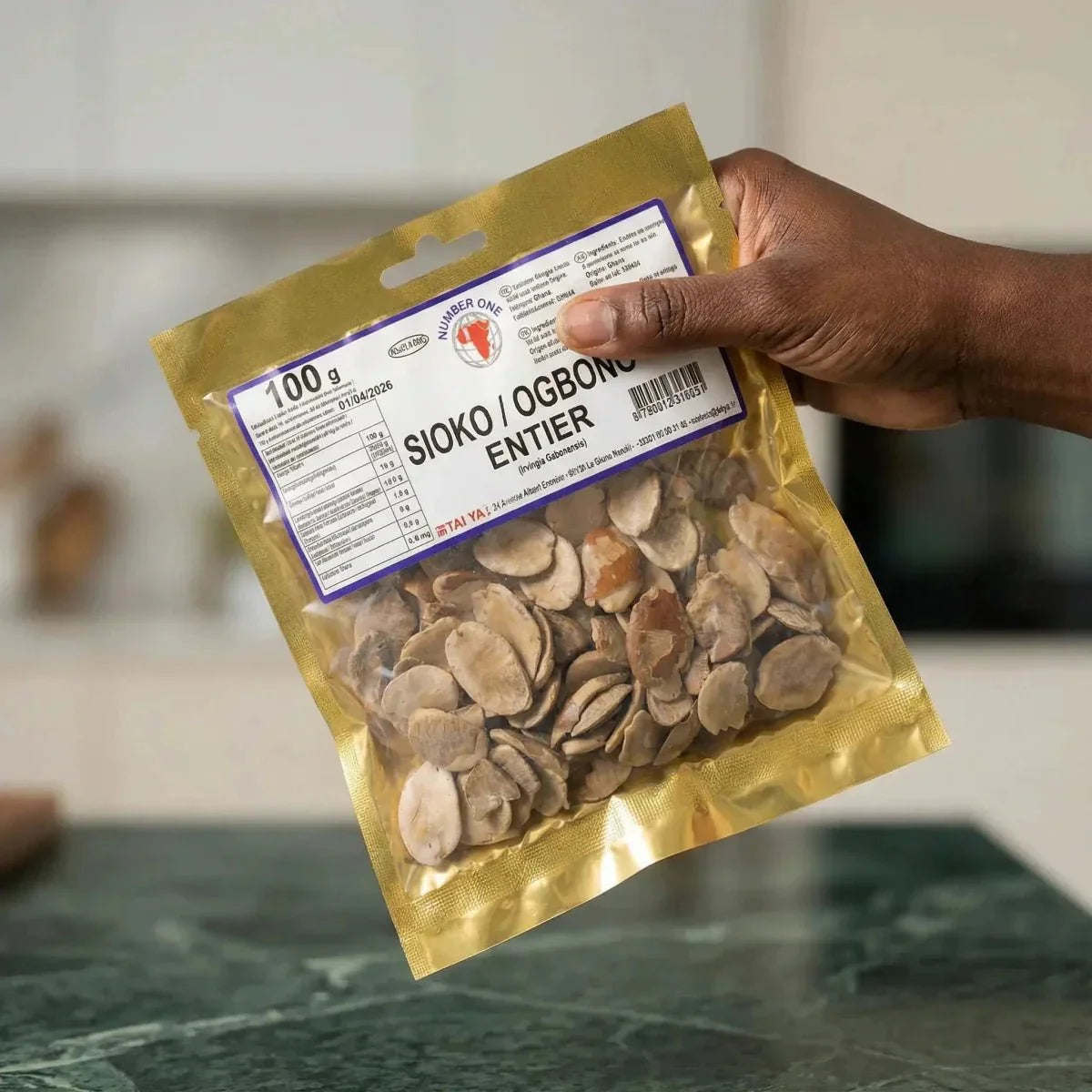 Sachet doré de Sioko Entier (Ogbono) NUMBER ONE tenu par une main, affichant ingrédients.