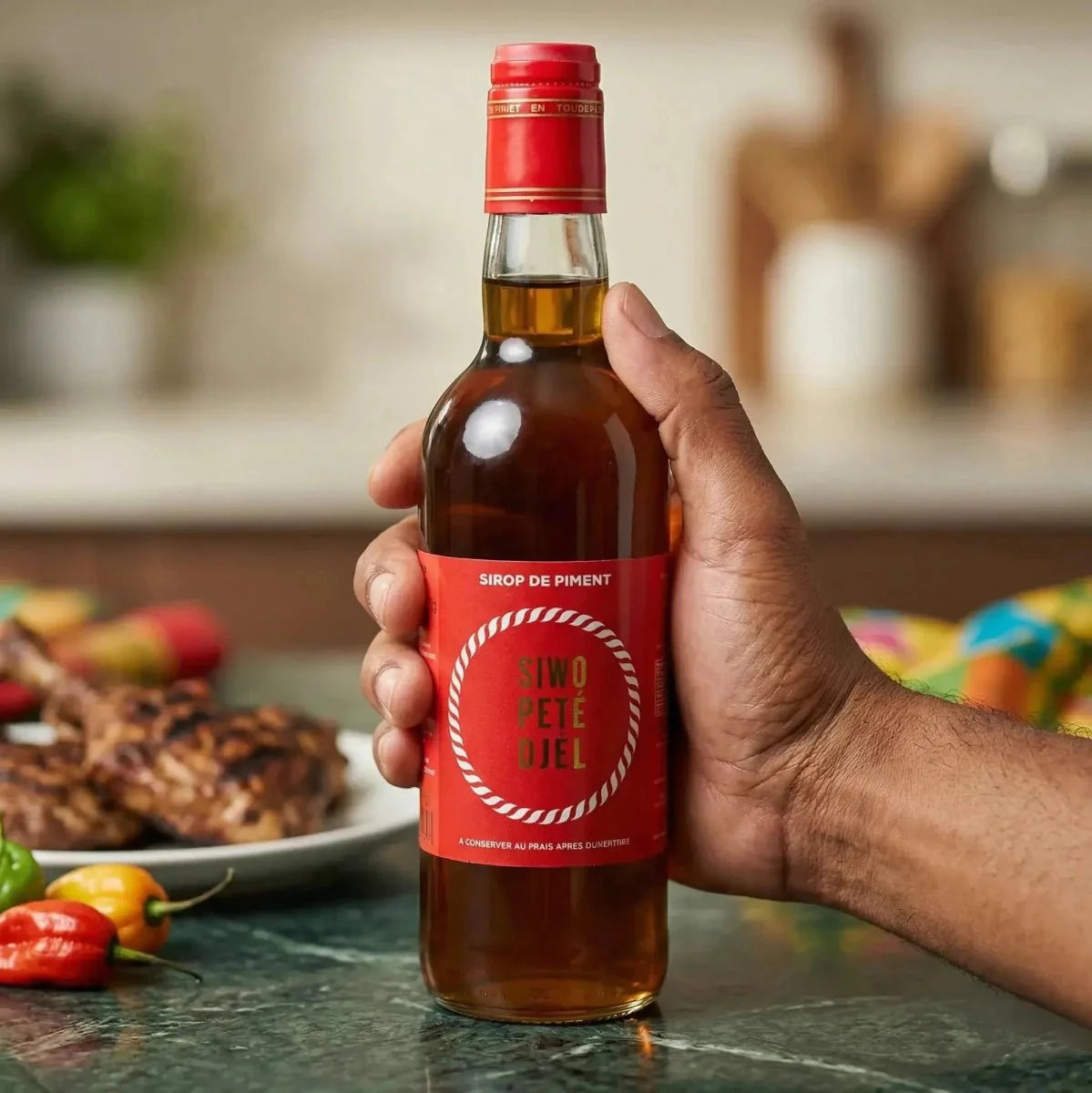 Sciroppo di peperoncino rosso Siwo Pete Djèl, con un'etichetta rossa e bianca, presentato in una mano.
