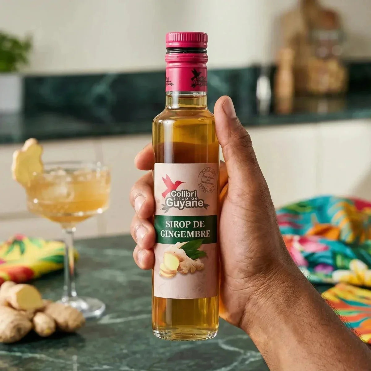 Sirop gingembre DELICES DE GUYANE : gros plan sur une main tenant la bouteille, cocktail.